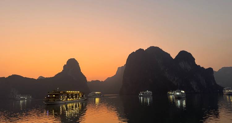 Cruceros en una bahía al atardecer con islas de piedra caliza.
