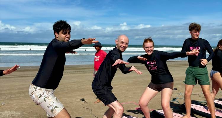 Grupo de surfistas posando frente a una playa.