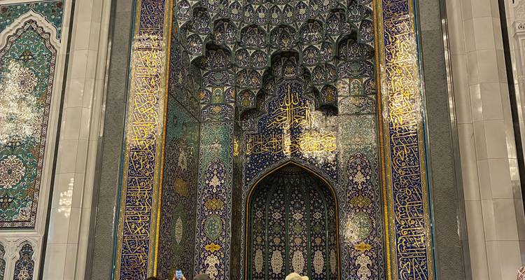 Gros plan sur un carrelage complexe et une calligraphie arabe dans une mosquée.