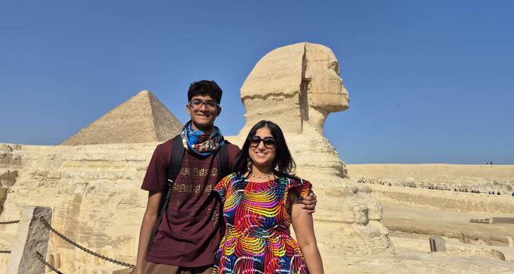 Visitors posing in front of the Sphinx and Pyramid, under a clear blue sky.