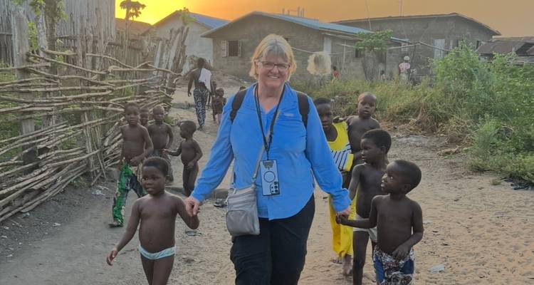 Mujer caminando with niños en un pueblo rural al atardecer.