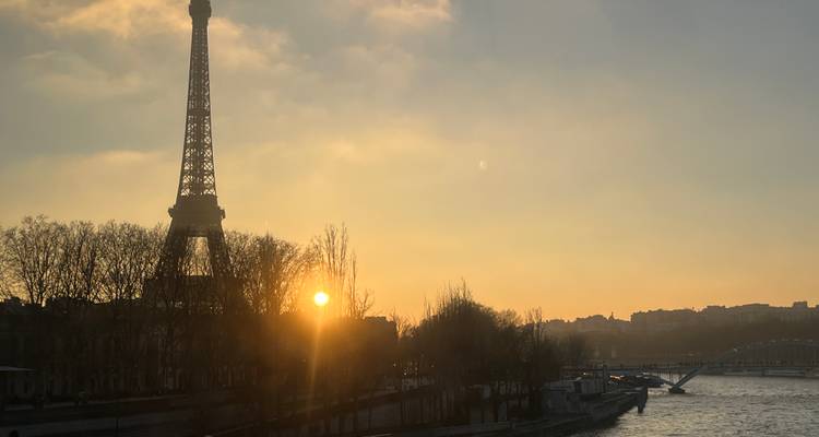Torre Eiffel al atardecer con el río en primer plano.