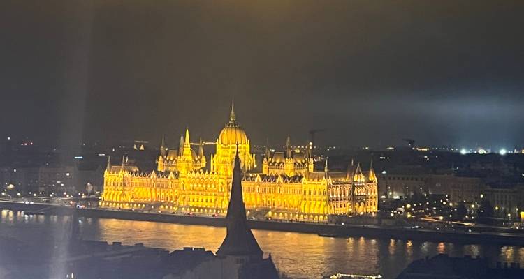 Edificio histórico iluminado por la noche reflejándose en un río.