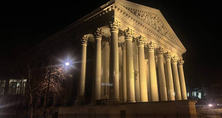 Élégant bâtiment historique avec des colonnes illuminé la nuit.