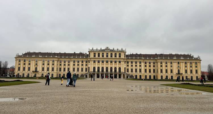 Un vaste palais avec des touristes, ciel couvert.