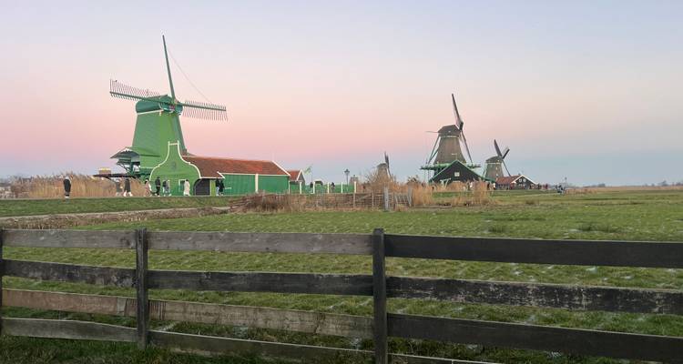Moulins à vent dans un cadre rural pendant l'aube aux teintes roses.