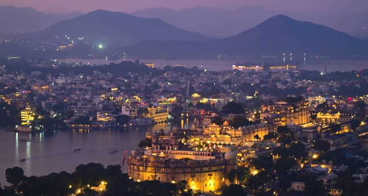 Paisaje urbano de Udaipur al crepúsculo con palacio y lagos.