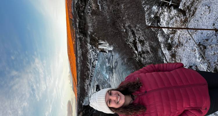 Mujer con ropa de invierno frente a una cascada.
