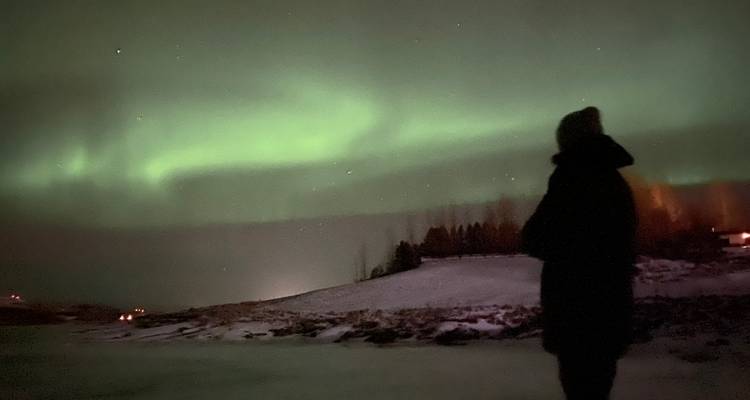 Personne silhouettée devant les aurores boréales.