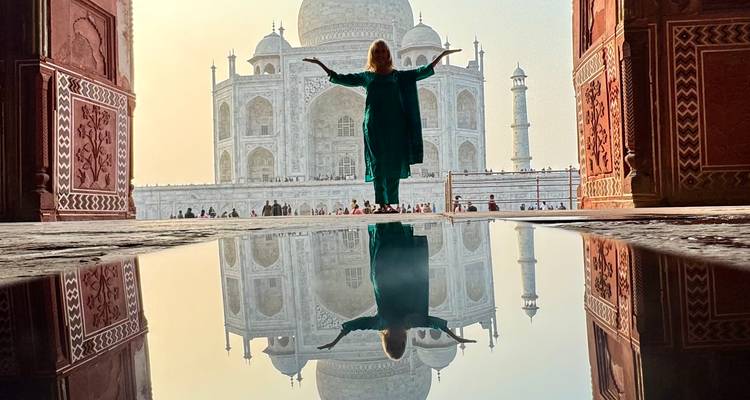 Une personne debout devant le Taj Mahal avec les bras levés.