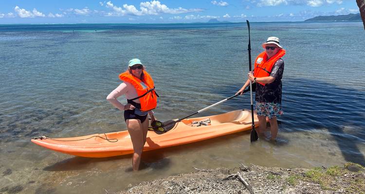 Dos personas navegando en kayak en aguas cristalinas con chalecos salvavidas.