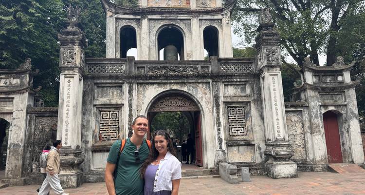 Un couple posant devant une porte en pierre ancienne avec des sculptures complexes.