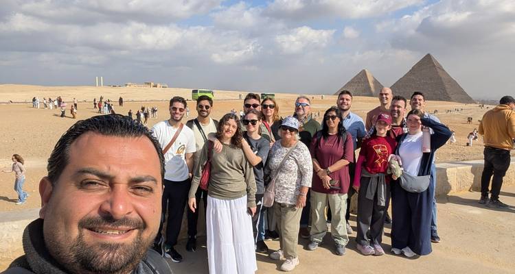 Groupe touristique avec pyramides et paysage désertique en arrière-plan.