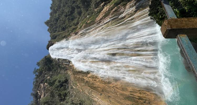 Grande cascade dégringolant le long d'une falaise rocheuse avec des arbres à proximité.
