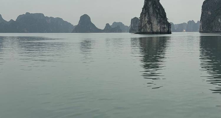 Formaciones cársticas de piedra caliza reflejadas en aguas tranquilas, típicas de la Bahía de Halong.