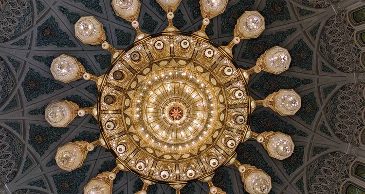 Lámpara de araña intrincada con patrones en el techo, vista desde abajo.
