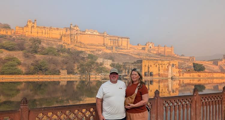 Pareja de pie frente al Fuerte de Ámbar junto a un lago.