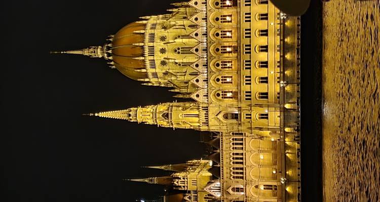 Bâtiment du Parlement illuminé la nuit, reflété dans la rivière.