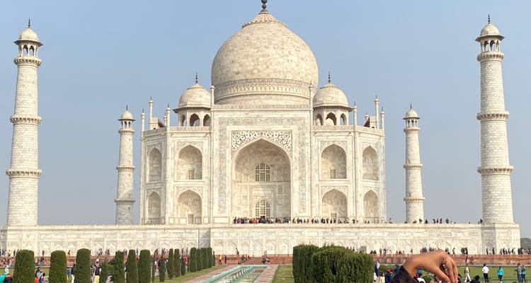 De Taj Mahal met zijn reflectie in het lange bassin ervoor onder een heldere hemel.