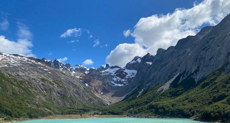 Vue panoramique d'un lac glaciaire bleu entouré de montagnes escarpées.