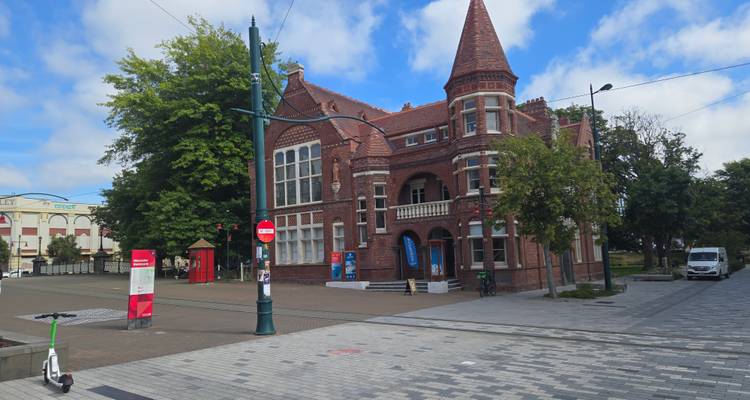 Bâtiment historique en brique avec architecture gothique dans un environnement urbain.