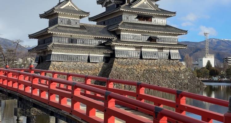 Matsumoto-Burg mit einer roten Brücke unter einem strahlend blauen Himmel.