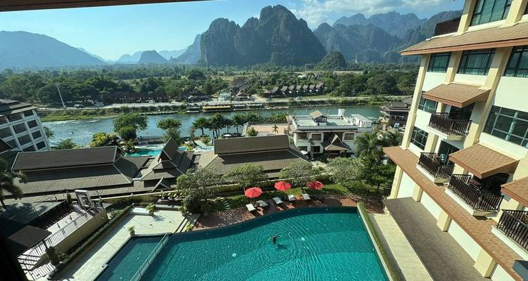 Vista aérea de un hotel con piscina y montañas al fondo.