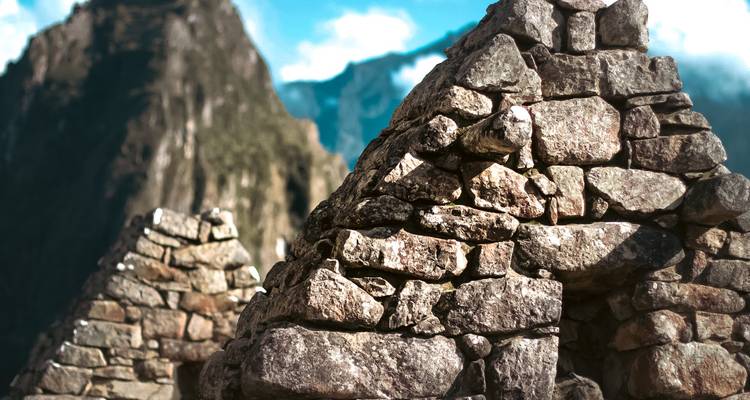 Estructuras de piedra apilada with majestuosas montañas de fondo.