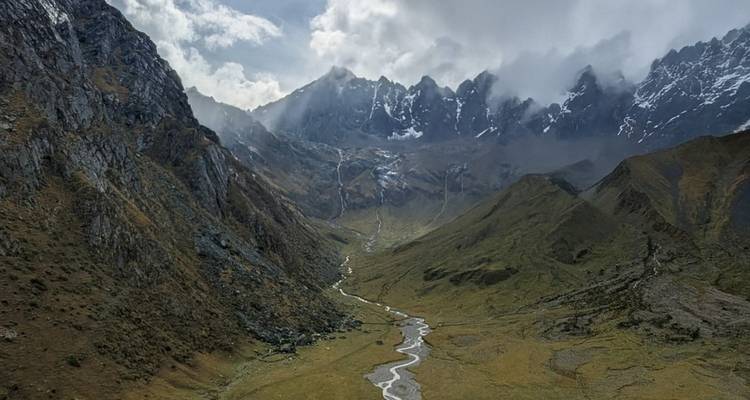 Un amplio valle enclavado entre cordilleras bajo un cielo dramático y nublado.