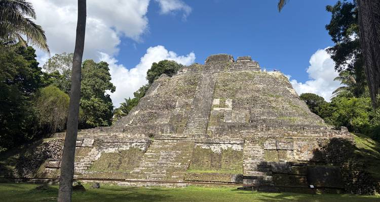 Ruina de pirámide de piedra en un área verde exuberante capturada bajo un cielo azul.