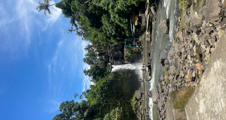 Touristen erkunden einen Wasserfall in einer üppigen Dschungellandschaft.