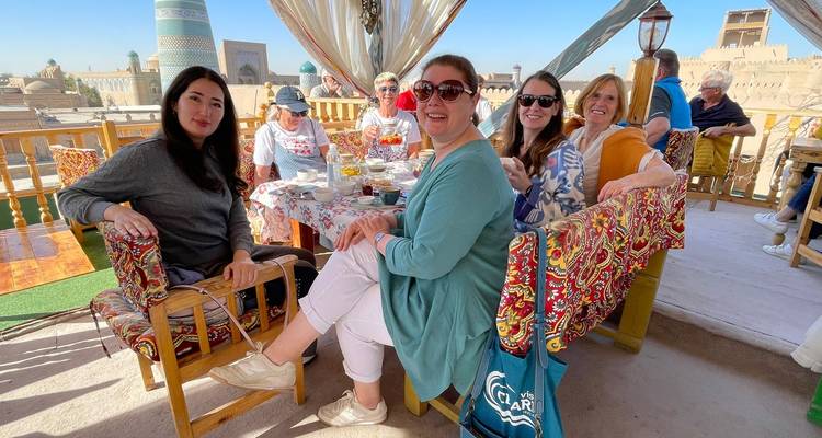 Grupo de mujeres disfrutando de una comida en un restaurante al aire libre con vistas a la ciudad.