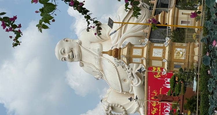 Große weiße lachende Buddha-Statue mit dekorativen Elementen unter blauem Himmel.