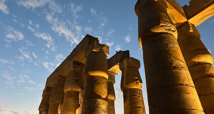Colonnes antiques illuminées contre un ciel crépusculaire.