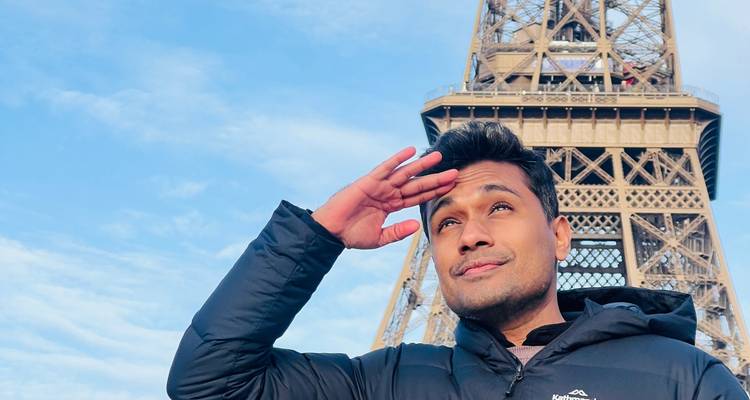 Persona saludando con la Torre Eiffel de fondo.