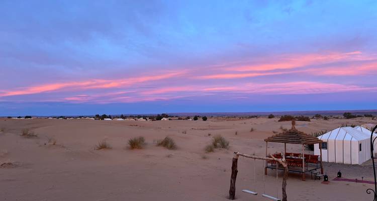 Wüsten-Campingplatz mit farbenfrohem Sonnenuntergang und Zelten.