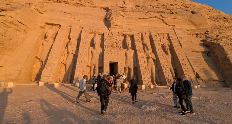 Facade of a temple with tall statues and people.