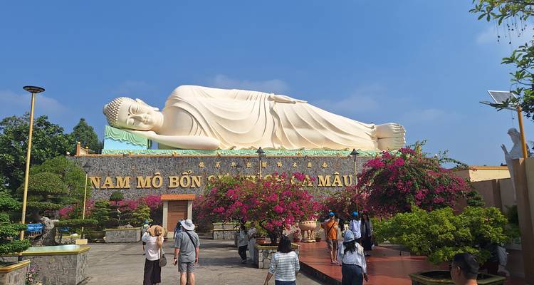 Groot standbeeld van een liggende Boeddha met verschillende bezoekers die rondlopen.