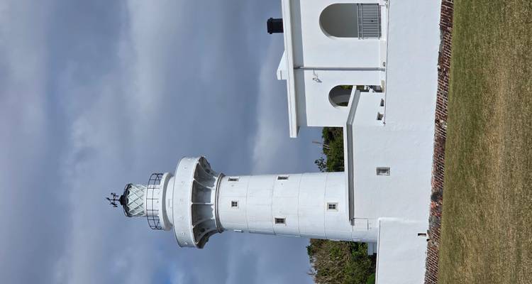 Un phare blanc avec un ciel bleu et des nuages.