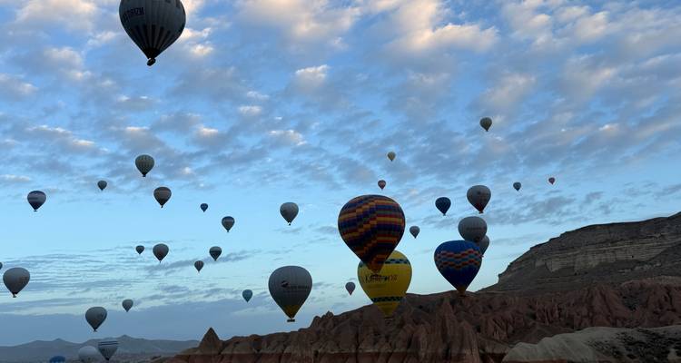 Numerosos globos aerostáticos sobre un paisaje rocoso durante el amanecer.