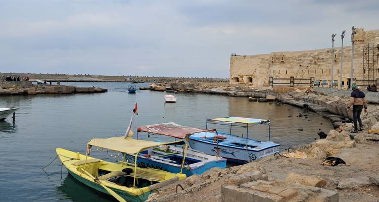Des bateaux colorés dans un port à côté d'un fort de pierre ancien.