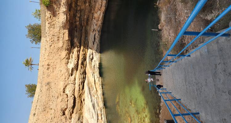 Borde de un sumidero lleno de agua, con personas descendiendo escalones.