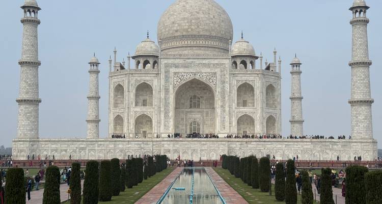 Vue iconique du Taj Mahal avec des touristes au premier plan.