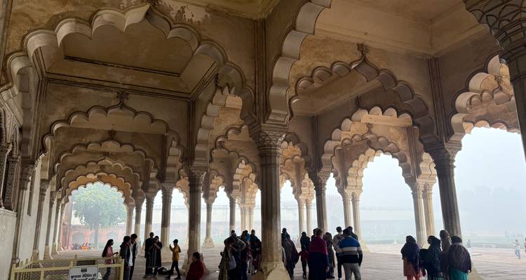 Groupe de touristes dans un bâtiment historique avec des arches et un arrière-plan brumeux.