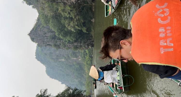 Toerist in een boot op een rivier met kalkstenen karstformaties op de achtergrond.