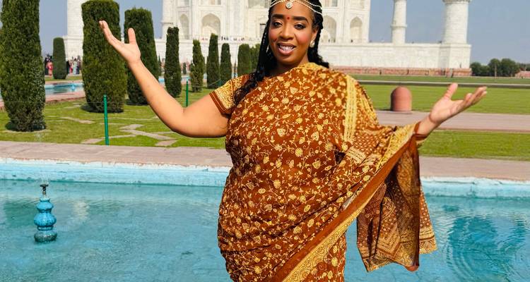 Femme en sari traditionnel posant joyeusement devant le bassin réfléchissant avec le Taj Mahal en arrière-plan.