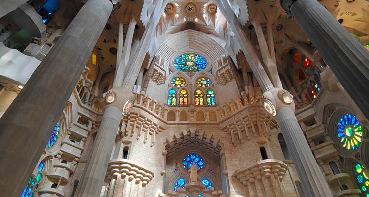 Vista interior impresionante de la nave de la Sagrada Família con vidrieras multicolores resplandecientes y columnas elevadas.