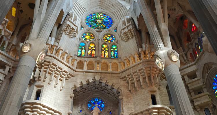 Brillantes rosetones de vidrieras iluminan la elevada nave de la Sagrada Familia desde un ángulo interior.