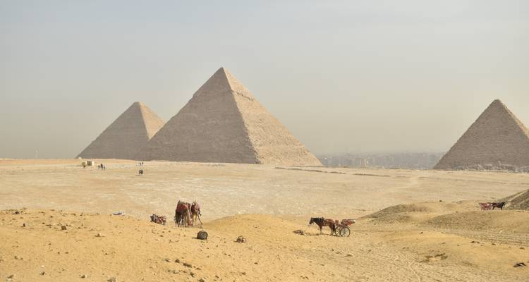 Vue panoramique des trois Grandes Pyramides de Gizeh se fondant dans la brume du désert.