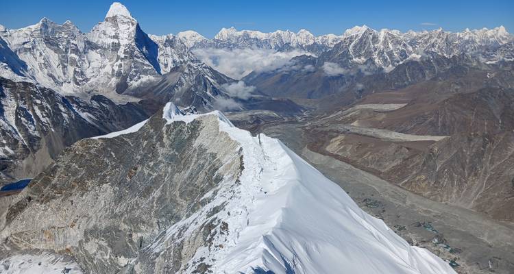 Vue aérienne époustouflante d'une crête enneigée effilée comme un rasoir menant vers les géants himalayens imposants et les vallées en contrebas.